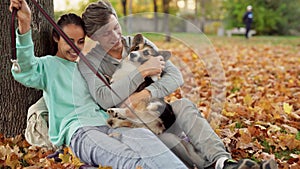 Loving Couple making selfie on smartphone with cute tricolor Welsh Corgi Dog In City Park hugging relaxing enjoying warm