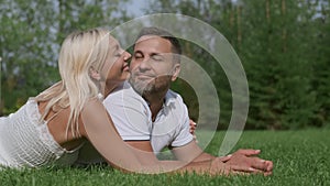 Loving couple man and woman lie on the grass touching their noses to each other