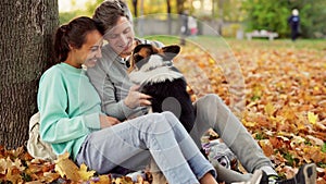 Loving Couple Man And Woman sitting with Welsh Corgi Dog In City Park hugging