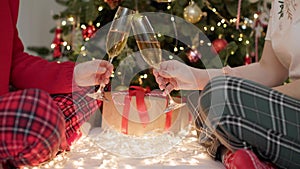 loving couple in pajamas holds glasses of sparkling champagne wine celebrating