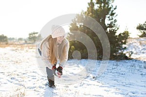 Loving couple play snowballs in winter in the forest. Girl sculpts and throws snowballs. Laugh and have a good time