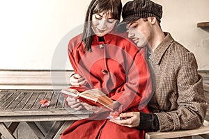 Loving couple reading a book in the bar. Two gifts with red bow are placed on the table