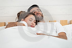 Loving couple relaxing and hugging in bed, love and relationships concept