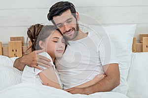 Loving couple relaxing and hugging in bed, love and relationships concept