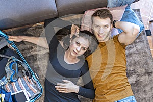 Loving couple is relaxing lying on the floor at home among the suitcases