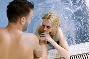 Loving couple relaxing in the spa by the swimming pool