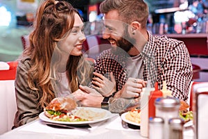 Loving couple in retro bright street food cafe hugging