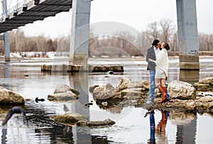 Loving couple on the river bank embraces, kisses