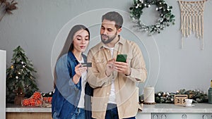 Loving couple shops online for Christmas deals woman kisses content husband.