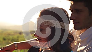 Loving couple sit on the grass in the mountains and look at the nature.