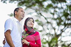 Loving couple sitting down on floral field in park, warm sunny day, enjoying family, romantic date, happiness and love co