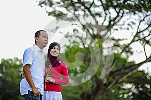 Loving couple sitting down on floral field in park, warm sunny day, enjoying family, romantic date, happiness and love co