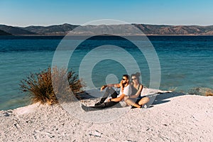 Loving couple sitting on the edge of the cliff by the sea. Wedding travel. Honeymoon trip. Boy and girl at the sea
