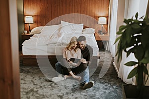 Loving couple sitting on the floor in bedroom and using tablet