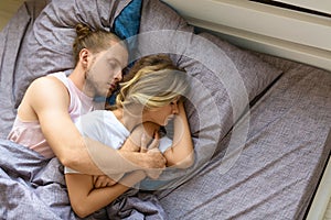 A loving couple is sleeping in bed - husband hugs his wife from the back. Recovery and healthy sleep concept.