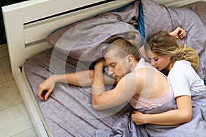 Loving couple is sleeping in bed - wife hugs her husband from the back. Recovery and healthy sleep concept.