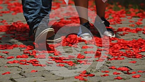 Loving couple slowly walking along road with rose petals throwing them with feet