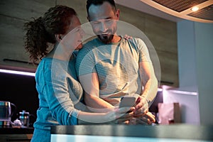 Loving couple with smartphone in kitchen stock photo