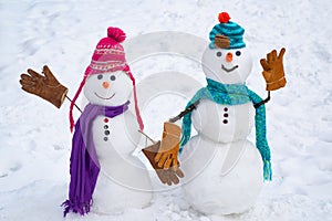 A loving couple of snowmen. Christmas background with couple of snowman. Snowman couple outdoor. Cute snow man in hat