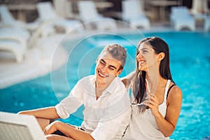 Loving couple spending vacation on tropical resort swimming pool.Newlyweds honeymoon on seaside.