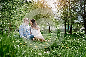 Loving couple in the spring garden sitting on the grass