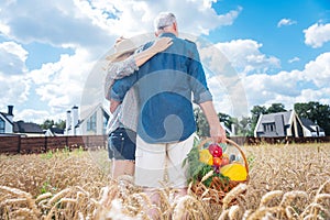 Loving couple standing in the field near their little detached house