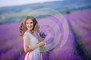 A loving couple standing in a lavender field and hugging. Beautiful bride dressed in luxurious wedding dress. Bride and