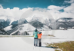 Milujúci pár stojaci a pri pohľade na krásne zasnežené vrcholky hôr. Panoramatický výhľad. Pohľad zozadu