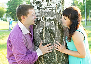 A loving couple standing near a tree