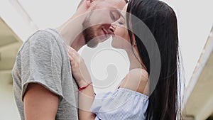 A loving couple are standing under a bridge hugging and kissing.