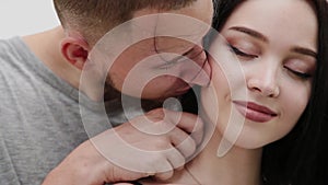 A loving couple are standing under a bridge hugging and kissing.