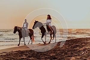 A loving couple in summer clothes riding a horse on a sandy beach at sunset. Sea and sunset in the background. Selective