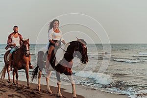 A loving couple in summer clothes riding a horse on a sandy beach at sunset. Sea and sunset in the background. Selective