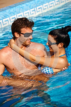 Loving couple in swimming pool smiling