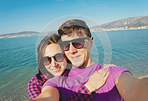 Loving couple taking photographs self-portrait on beach