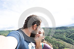loving couple taking a selfie while kissing in outdoor. Boyfriend with a beard. Family traveling together