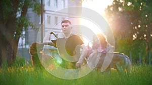 Loving couple with their dogs having a rest outdoors - throws a stick to a dog at sunset