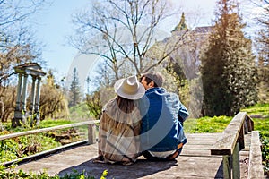 Loving couple of tourists relaxing by Olesko Castle in spring garden sitting on bridge. Travelling in Western Ukraine.