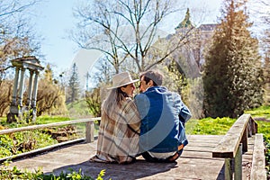 Loving couple of tourists relaxing by Olesko Castle in spring garden sitting on bridge. Travelling in Western Ukraine.