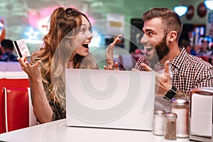 Loving couple using laptop computer holding credit card