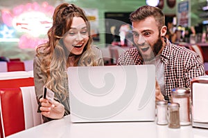 Loving couple using laptop computer holding credit card