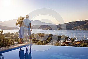 Loving couple on vacation time enjoys the summer sunset over the Aegean Sea