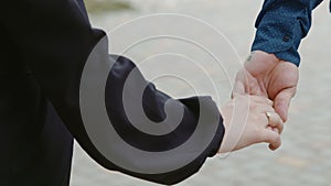 A loving couple walking hand in hand in the park. Guy and girl close-up hands meeting on a city street. A beautiful