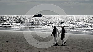 Loving couple walking hand in hand on a sandy beach towards the beautiful expanse of the ocean