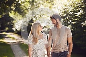 Loving Couple Walking Holding Hands Along Countryside Path In Summer Together