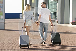 Loving couple walking to airport entrance with luggage