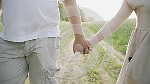 A loving couple walks along the road along the field in the rays of the setting sun.