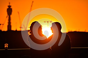 loving couple watching beautiful bright romantic sunset, sitting leaning against blue sport car. The fields around them. The youn