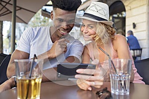 loving couple watching smart phone during aperitif