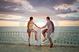 Loving couple watching sunset at the sea